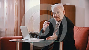 Elderly grandfather - old grandfather talking to a computer on a table in his room