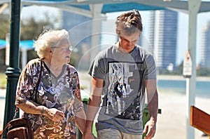 Elderly grandmother day out seaside with grandson walking beach