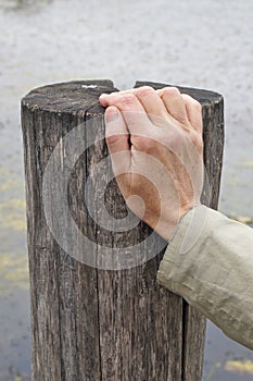 The elderly grandmother rests his right hand on a wooden pillar photo