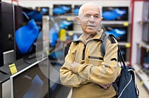 elderly grayhaired man pensioner looking counter with modern digital televisors in showroom of digital goods store