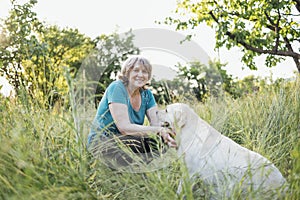 Elderly grayhaired woman with her dog in the park