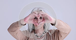 Elderly grayhaired woman showing heart shaped gesture with hands 4k movie slow motion