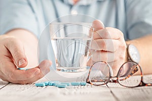 Elderly hand is holding blue tablets with white background
