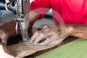 Elderly hand with a sewing machine.