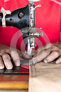 Elderly hand with a sewing machine.