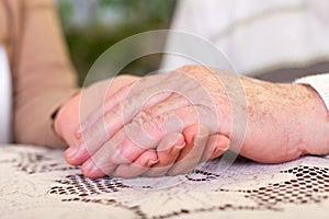 Elderly hands holding carer`s hands