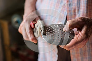 Elderly hands with pliers in an old workshop