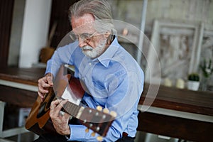 Elderly handsome man business style happy smile play acoustic guitar In living room to relax from tedious work. Male senior