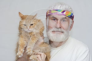 an elderly handsome man with a gray beard holds a Big red Siberian cat