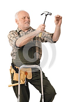 Elderly handyman hammering nail