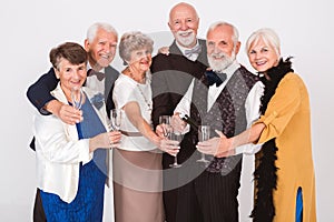 Elderly happy friends opening a bottle of champagne