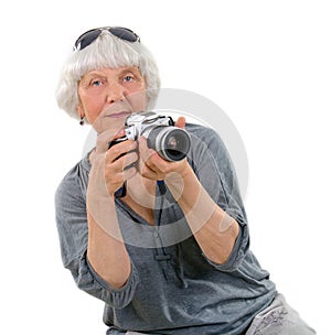 Elderly happy pleasant woman taking pictures with a camera on a white background. Active pension. Leisure and hobbies of people ag