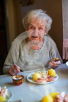 An elderly happy woman dines at home.