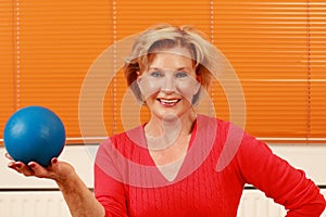 Elderly happy woman holding a blue gymnastic ball
