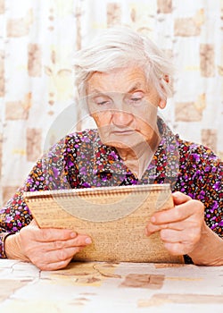 Elderly happy woman read something from the book