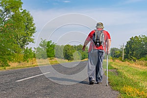 Elderly hiker walking on a roadside in Ukrainian rural area