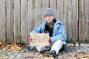 Elderly homeless woman sitting on the street