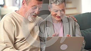 The elderly husband and wife happily chat with their families on the computer. Video chat concept from the computer