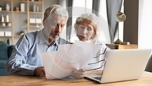 Elderly husband and wife read documents pay bills online