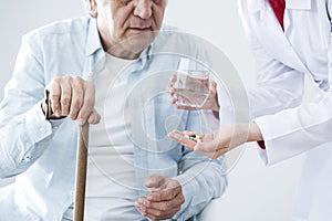 Elderly ill man and nurse giving medicine