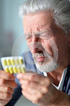 Elderly ill man with pills in hands