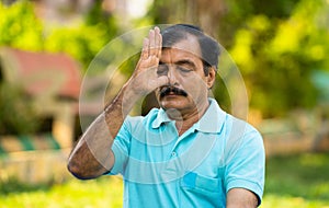 Elderly Indian senior man doing nostril breathing yoga or pranayama exercise - concept of zen, healthy lifestyle and