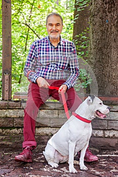 Elderly Jewish Man In Park Woods Sitting with White Pitbull