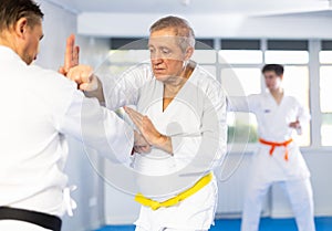 Elderly karate fighter engaging kumite with male rival