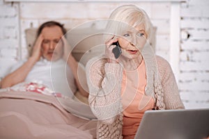 Elderly lady calling emergency for ill husband