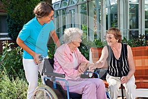 Elderly lady with a carer talking to a friend