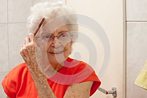 Elderly Lady Combing her hair in front of a Mirror