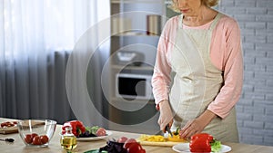 Elderly lady cutting salad, vegetarian nutrition, health care, culinary hobby