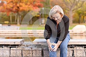 Elderly lady grabbing her knee in pain