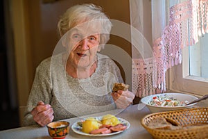 An elderly lady has dinner sitting at the table.