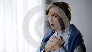 Elderly lady having asthma attack symptoms, hard to breath and pain in chest photo