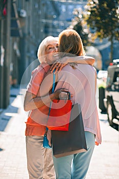 Elderly lady hugging her daughter and smiling stock photo