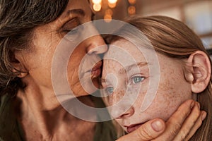 Elderly lady kissing with tenderness her lovely freckled granddaughter