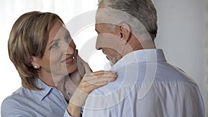 Elderly lady with perfect skin looking husband, husband stroking her happy face