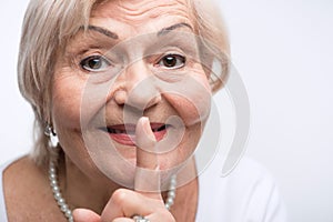 Elderly lady putting finger on her mouth