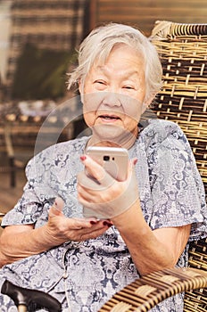 Elderly lady seated at home learning how to use the smartphone.
