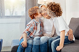 Elderly lady smiling while grandsons kissing her