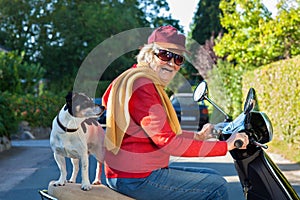 Elderly lady taking her dog for a scooter ride