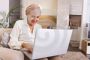 Elderly lady working with laptop. Portrait of beautiful older woman working laptop computer indoors. Senior woman using laptop at