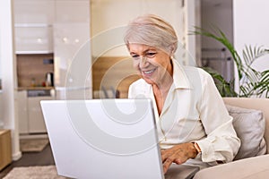 Elderly lady working with laptop. Portrait of beautiful older woman working laptop computer indoors. Senior woman using laptop at