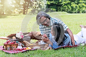 Elderly lifestyle concept. Happiness couple relax together in the public park. Husband embracing and holding red apple for