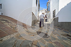 Elderly local man climbing slope narrow street of Comares, Malaga, Spain