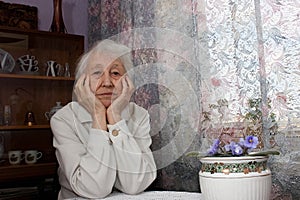 Elderly lonely woman depressed sitting at the table