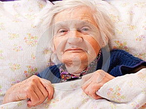 Elderly lonely woman rests in the bed