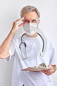 Elderly male doctor wearing goggles, face protective mask for protection from virus disease