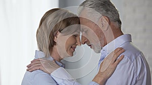 Elderly male and female looking at each other, putting foreheads together, happy